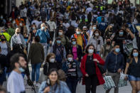 FILE - People wearing face masks to protect against the spread of coronavirus walk in downtown Madrid, on March 31, 2021. With one of Europe's highest vaccination rates and its most pandemic-battered economies, the Spanish government is laying the groundwork to approach the virus in much the same way countries deal with flu or measles. (AP Photo/Manu Fernandez, File)