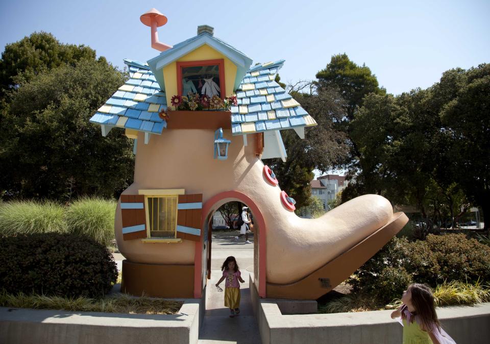 In this photo take Thursday July 12, 2012, two girls play beneath "The Old Lady in the Shoe" at the entrance of Fairyland in Oakland, Calif. Growing up in the shadow of an icon is never a shoe-in, whether you’re a wannabe princess related to that attention-grabbing vamp Cinderella or a city living next door to fabled San Francisco. (AP Photo/Eric Risberg)