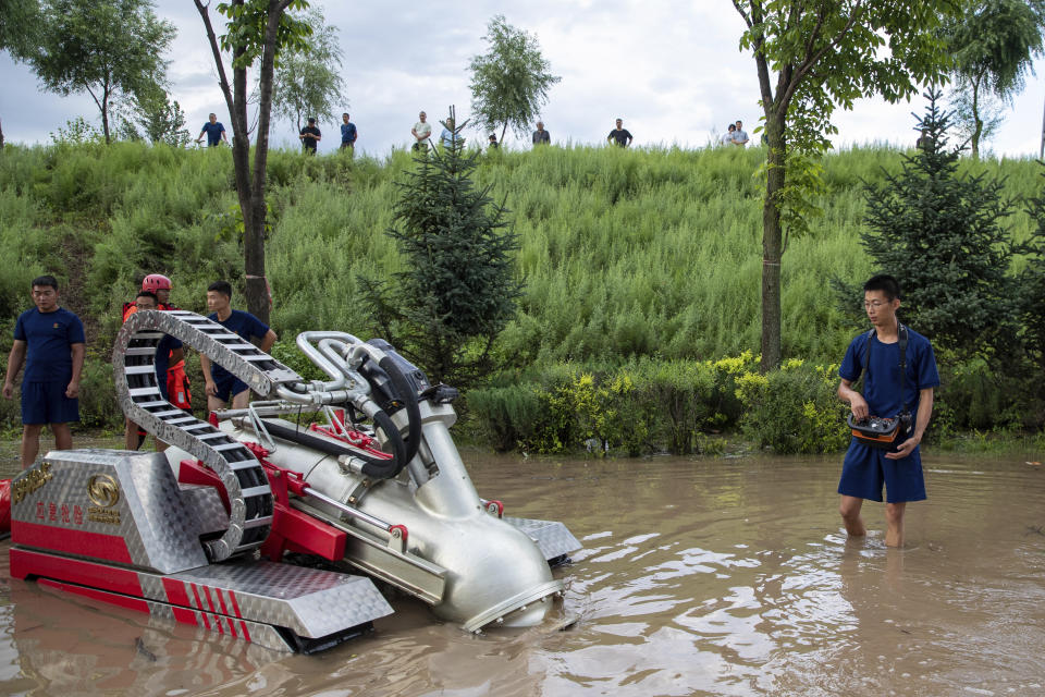 In this aerial photo released by Xinhua News Agency, firefighters operate a drainage machine near Dawan Village of Dong'an District, Mudanjiang in northeastern China's Heilongjiang Province, Aug. 5, 2023. Rain continued to pelt northeastern China in the wake of Typhoon Doksuri as authorities reported more fatalities and missing people while evacuating thousands more. (Zhang Tao/Xinhua via AP)