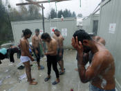 Migrants wash themselves in the Vucijak refugee camp outside Bihac, northwestern Bosnia, Thursday, Nov. 14, 2019. The European Union's top migration official is warning Bosnian authorities of a likely humanitarian crisis this winter due to appalling conditions in overcrowded migrant camps in the country. (AP Photo/Darko Vojinovic)