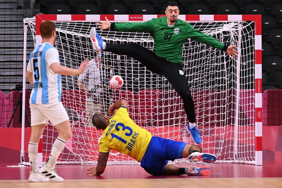 <p>Brazil's pivot Rogerio Moraes (C) shoots to score past Argentina's goalkeeper Juan Manuel Bar during the men's preliminary round group A handball match between Argentina and Brazil of the Tokyo 2020 Olympic Games at the Yoyogi National Stadium in Tokyo on July 30, 2021. (Photo by Martin BERNETTI / AFP)</p> 