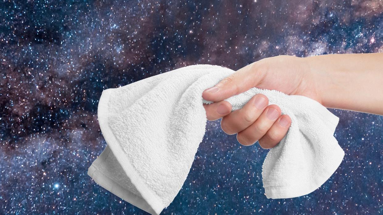  a hand holding a towel in front of a photograph of a galaxy 