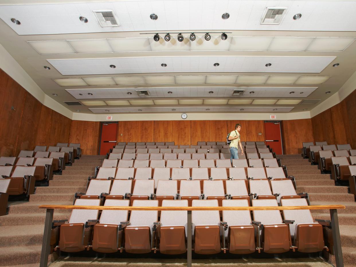 Student walking in empty classroom auditorium