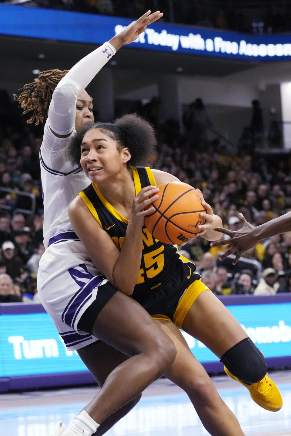 Iowa forward Hannah Stuelke, right, drives to the basket against Northwestern forward Paige Mott during the first half of an NCAA college basketball game in Evanston, Ill., Wednesday, Jan. 31, 2024. (AP Photo/Nam Y. Huh)