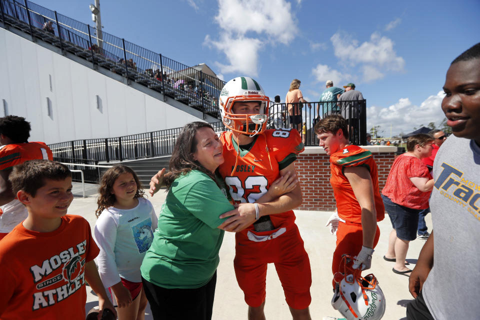 Melissa Guynn, a teacher at Mosley High, hugs kicker Connor Cunningham before the start of their football game against Pensacola, in the aftermath of Hurricane Michael in Panama City, Fla., Saturday, Oct. 20, 2018. (AP Photo/Gerald Herbert)