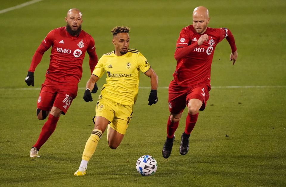 Nashville SC's Hany Mukhtar (10) drives the ball against Toronto FC's Nick DeLeon (18) and Michael Bradley.