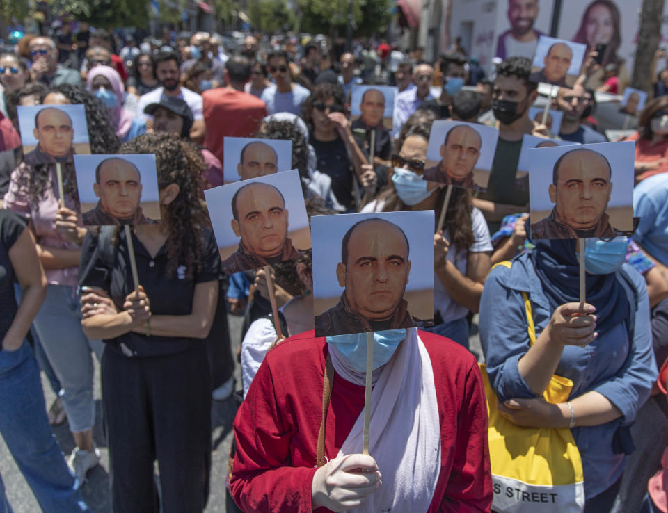 FILE - Angry demonstrators carry pictures of Nizar Banat, an outspoken critic of the Palestinian Authority, and chant anti-PA slogans during a rally protesting his death, in the West Bank city of Ramallah, Thursday, June 24, 2021. The family of the outspoken critic of the Palestinian Authority who died last year after allegedly being beaten by Palestinian security forces said Thursday, Dec. 15, 2022 that it has asked the International Criminal Court to investigate the death. (AP Photo/Nasser Nasser, File)