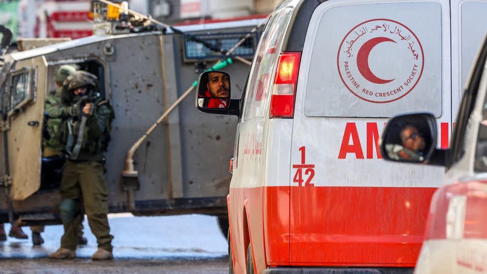 An Israeli soldier aims his weapon as Palestinian Red Crescent ambulances wait on December 13, 2023, in Gaza. - Jaafar Ashtiyeh/AFP/Getty Images/File