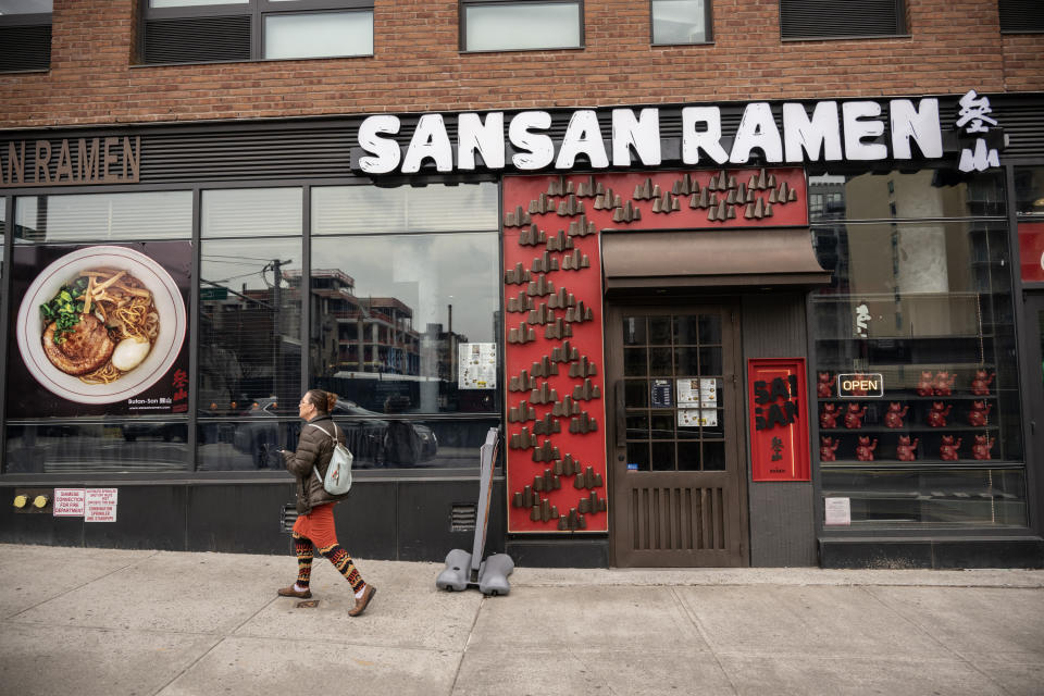 Un repartidor interactúa con una cajera remota mientras aparece en una pantalla en un establecimiento de Yaso Kitchen, un local de dumplings, en Nueva York, el 4 de abril de 2024. (Victor J. Blue/The New York Times)