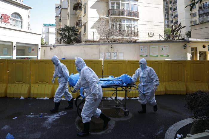 Medical workers move the body of a person who had died from COVID-19 at a hospital in Wuhan, China, on Feb. 16, 2020.