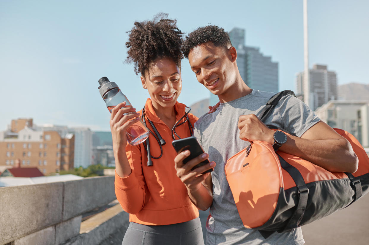 A man and a woman outdoors looking at a phone screen.