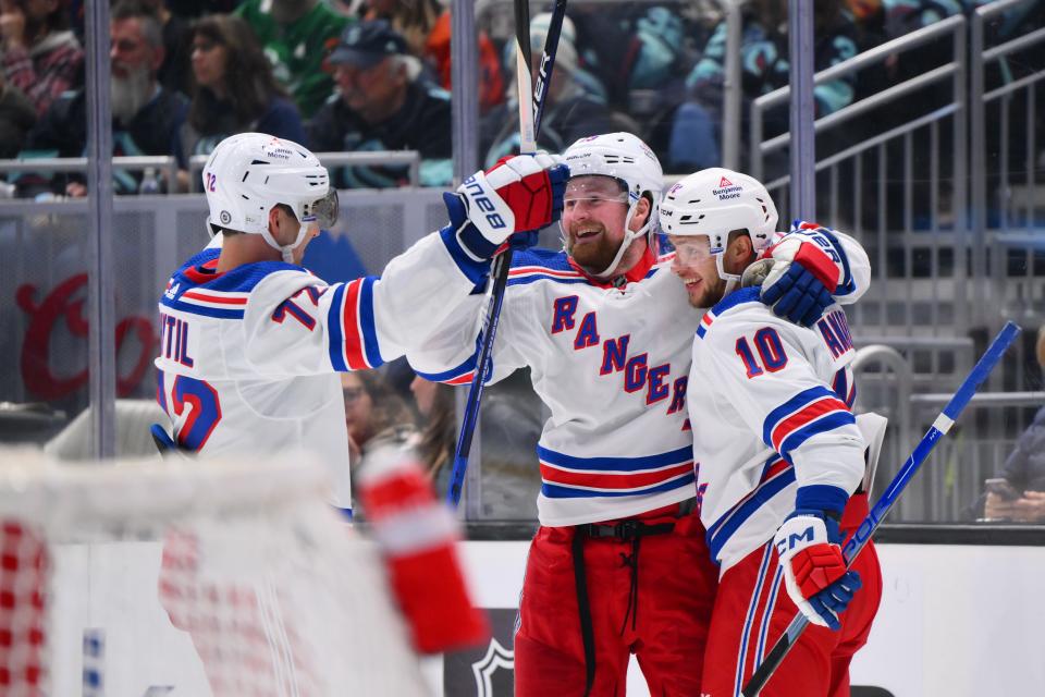 Oct 21, 2023; Seattle, Washington, USA; New York Rangers center Filip Chytil (72) and left wing Alexis Lafreniere (13) and left wing Artemi Panarin (10) celebrate after Panarin scored a goal against the Seattle Kraken during the third period at Climate Pledge Arena.