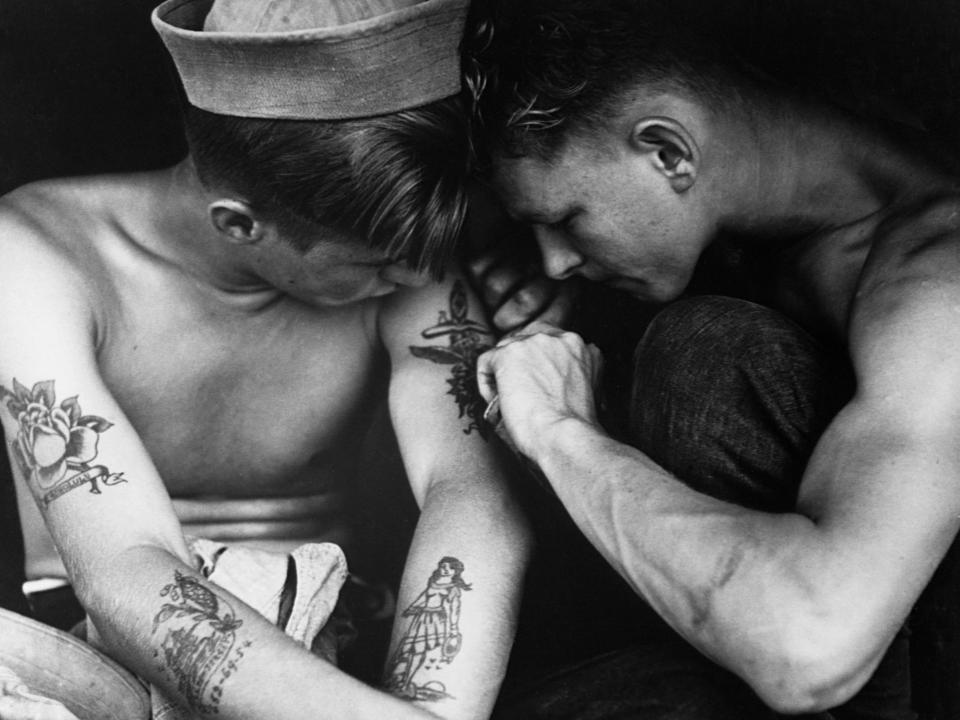 A sailor aboard the USS New Jersey inspects another sailor's tattoos