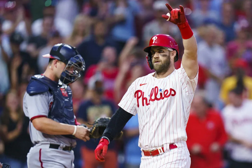 Philadelphia Phillies' Bryce Harper, right, reacts to his two-run home run, next to Washington Nationals catcher Riley Adams during the third inning of a baseball game Saturday, Sept. 10, 2022, in Philadelphia. (AP Photo/Chris Szagola)