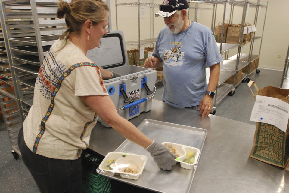 In this photo taken Friday, June 14, 2019, volunteers including retired accountant Ralph Nava, right, 69, pick up food packages to deliver to homebound families and dependent children in Santa Fe, N.M., at the headquarters for Kitchen Angels. An annual report on childhood well-being from the Annie E. Casey Foundation ranks New Mexico last among 50 states that includes measures of poverty, health care, education and family support. The number of children living in poverty has swelled over the past three decades in fast-growing, ethnically diverse states such as Texas, Arizona and Nevada as the nation's population center shifts south and west. (AP Photo/Morgan Lee)