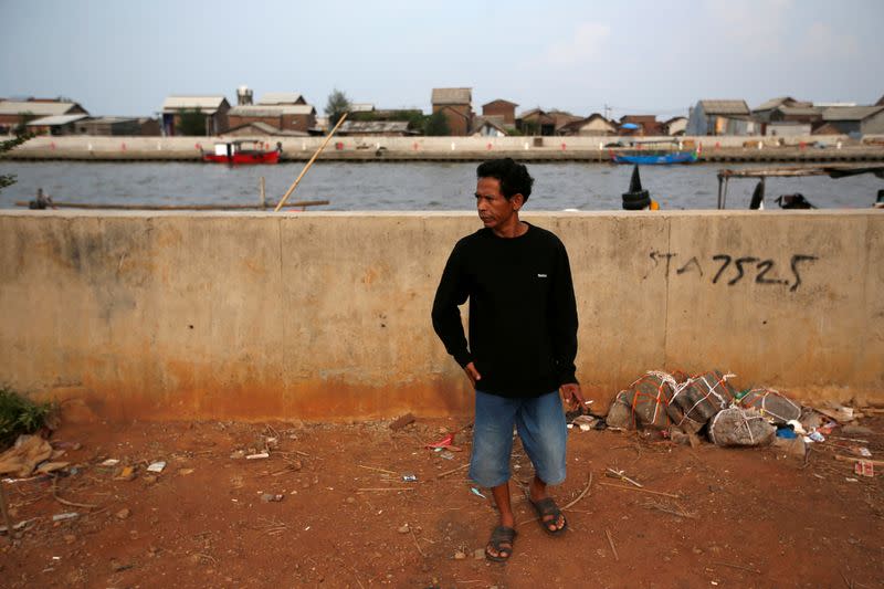 Miskan, a 44-year-old fisherman, walks near a port before going fishing at Tambaklorok village in Semarang