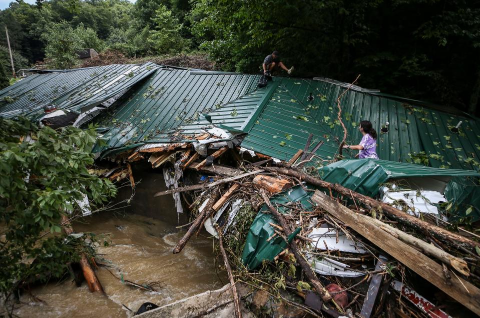 Kermit Clemons, atop his ex-mother-in-law's house outside Hazard, Ky., helps his ex-wife Lana Clemons retrieve family items. Flash flooding swept the trailer home off its foundation and carried it around 250 feet from its original location Thursday morning.  July 28, 2022