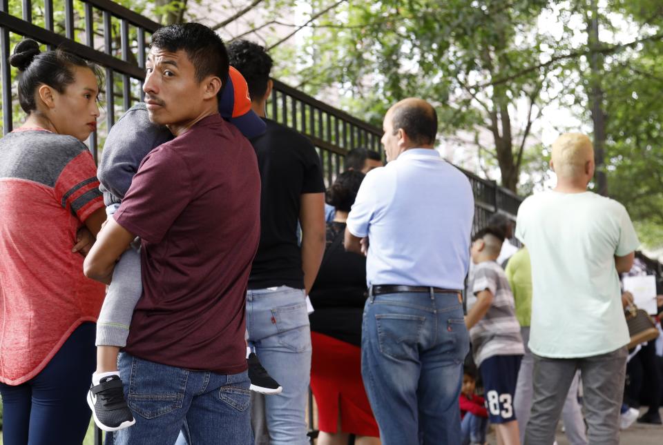 In this Wednesday, June 12, 2019 photo, Auner Cobon holds his son Andry while waiting in line outside the building that houses Immigration and Customs Enforcement and the Atlanta Immigration Court, in Atlanta. U.S. authorities are fast-tracking families' cases through immigration courts in a bid to discourage many from making the journey to seek refuge in the United States. (AP Photo/Andrea Smith)