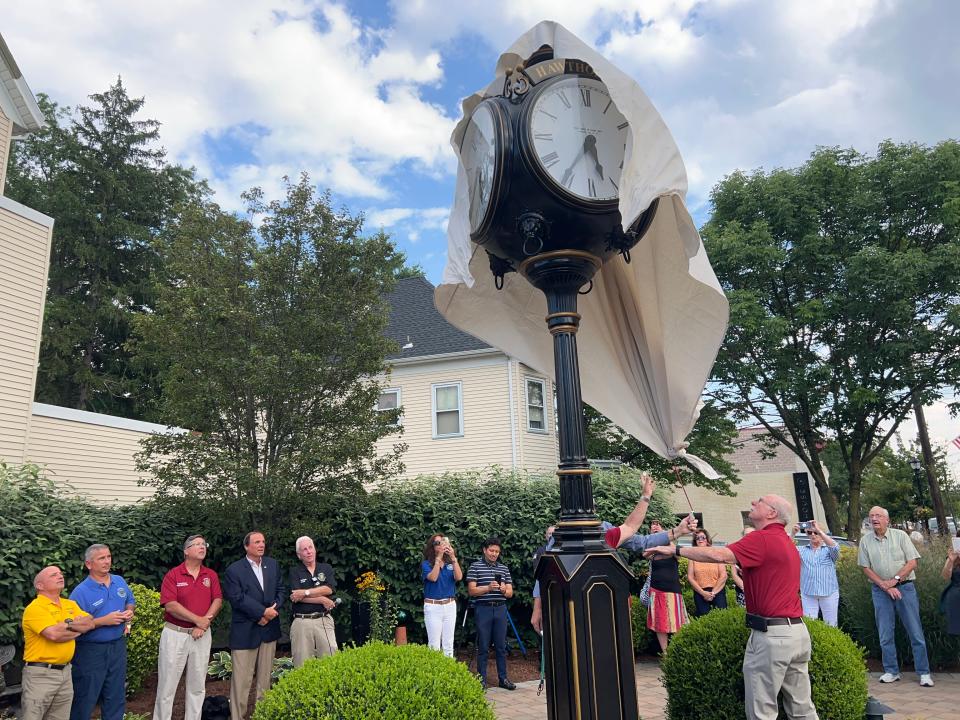 Mayor John Lane pulls off a canvas tarp to unveil the new street clock at the ceremony on Aug. 16.