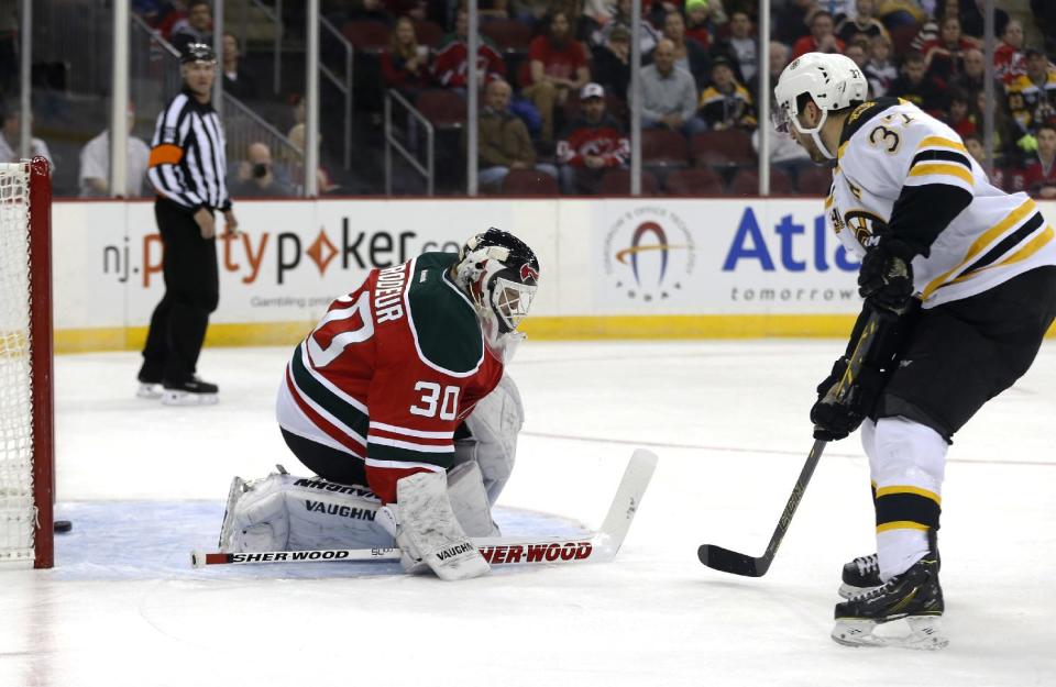 Boston Bruins center Patrice Bergeron, right, scores a goal on New Jersey Devils goalie Martin Brodeur during the first period of an NHL hockey game, Tuesday, March 18, 2014, in Newark, N.J. (AP Photo/Julio Cortez)