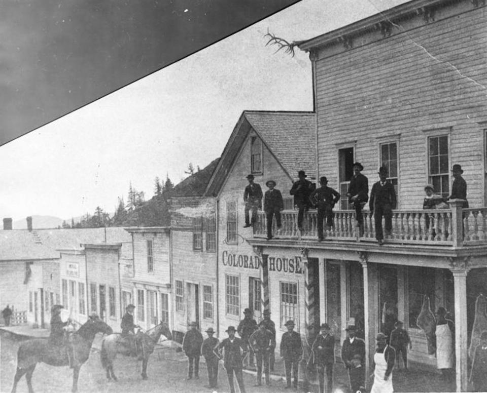 Men on horses, on the balcony, and standing along Potosi Street in Caribou in 1883.