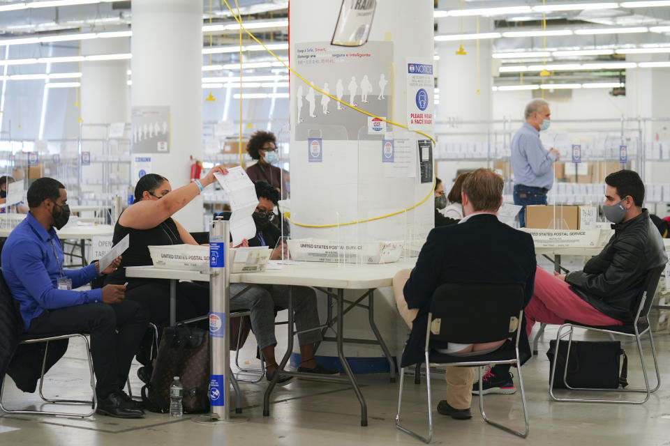 FILE - Polling workers inspect and count absentee ballots as poll watchers sit opposite, Nov. 10, 2020, in New York. Election officials across the country are bracing for a wave of confrontations in November as emboldened Republican poll watchers, many embracing former President Donald Trump's conspiracy theories about the 2020 election, flood polling places for the general election. (AP Photo/John Minchillo, File)