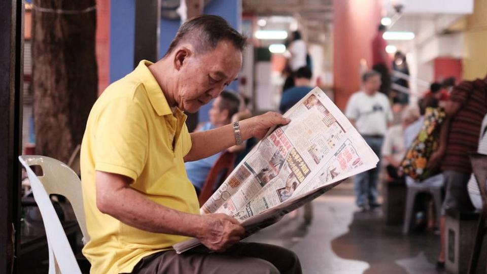 man reads a newspaper in Singapore