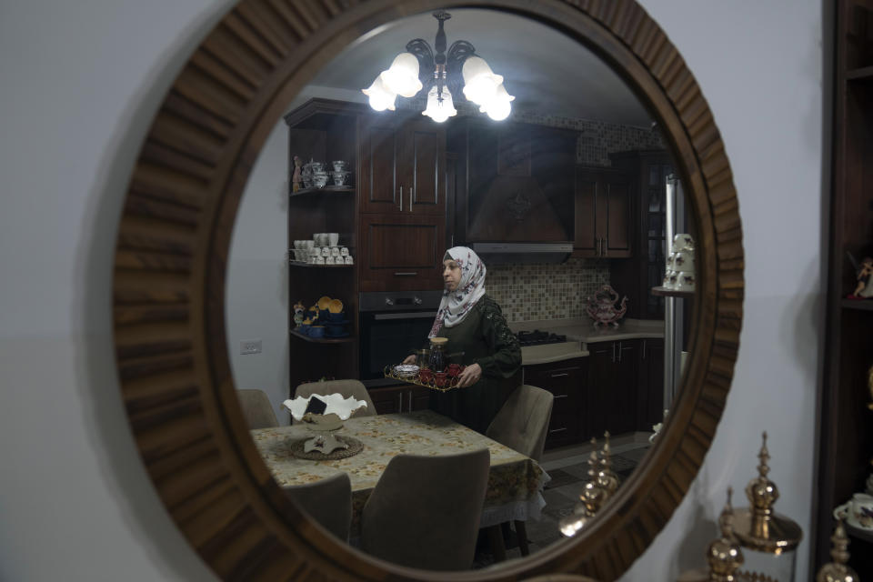 Dalal Awawdeh the wife of Khalil Awawdeh, a Palestinian prisoner in Israel, carries a tray with coffee in her kitchen in the West Bank village of Idna, Hebron, Tuesday, Aug. 9, 2022. Khalil Awawdeh who has refused food for 150 days to win his release by Israel has suddenly found himself thrust at the center of efforts to firm up a Gaza cease-fire because the Islamic Jihad group sought his release as part of Egyptian-brokered talks that ended three days of fighting between the Gaza-based militants and Israel over the weekend. (AP Photo/Nasser Nasser)