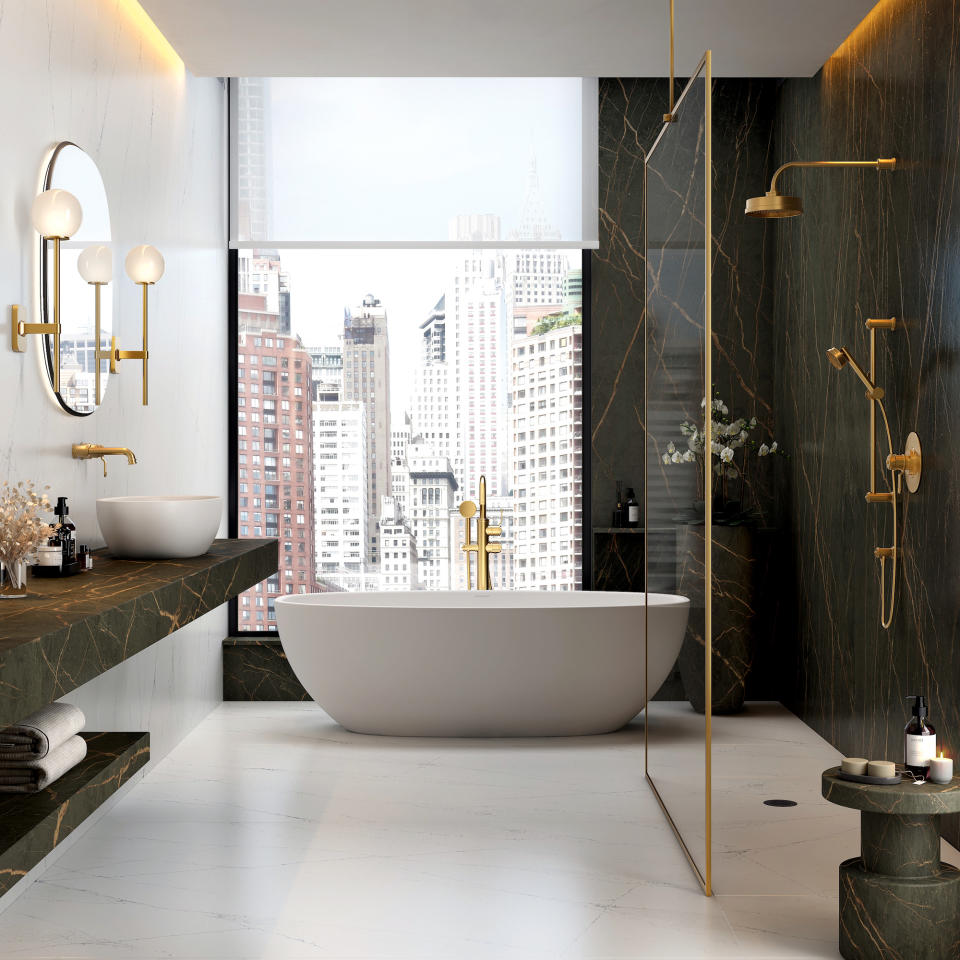 Luxe bathroom with large modern freestanding bath, gold fittings and dark grey marble walls