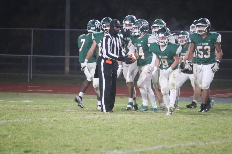 Oak Harbor's Jaxson Overmyer celebrates his interception as an official observes.