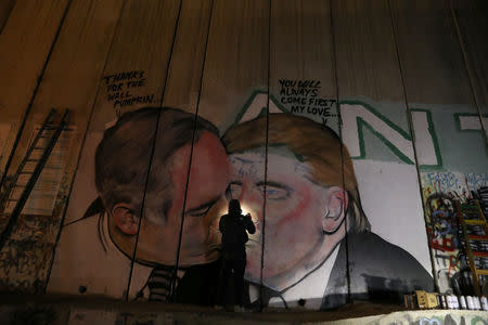 An Australian graffiti artist works on his mural depicting U.S. President Donald Trump and Israeli Prime Minister Benjamin Netanyahu on the controversial Israeli barrier in the West Bank city of Bethlehem October 28, 2017. Picture taken October 28, 2017. REUTERS/Ammar Awad