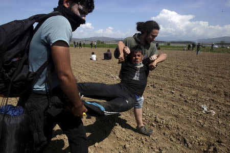 Protesting migrants carry an injured fellow migrant during clashes with Macedonian police next to a border fence at a makeshift camp for refugees and migrants at the Greek-Macedonian border near the village of Idomeni, Greece, April 10, 2016. REUTERS/Alexandros Avramidis