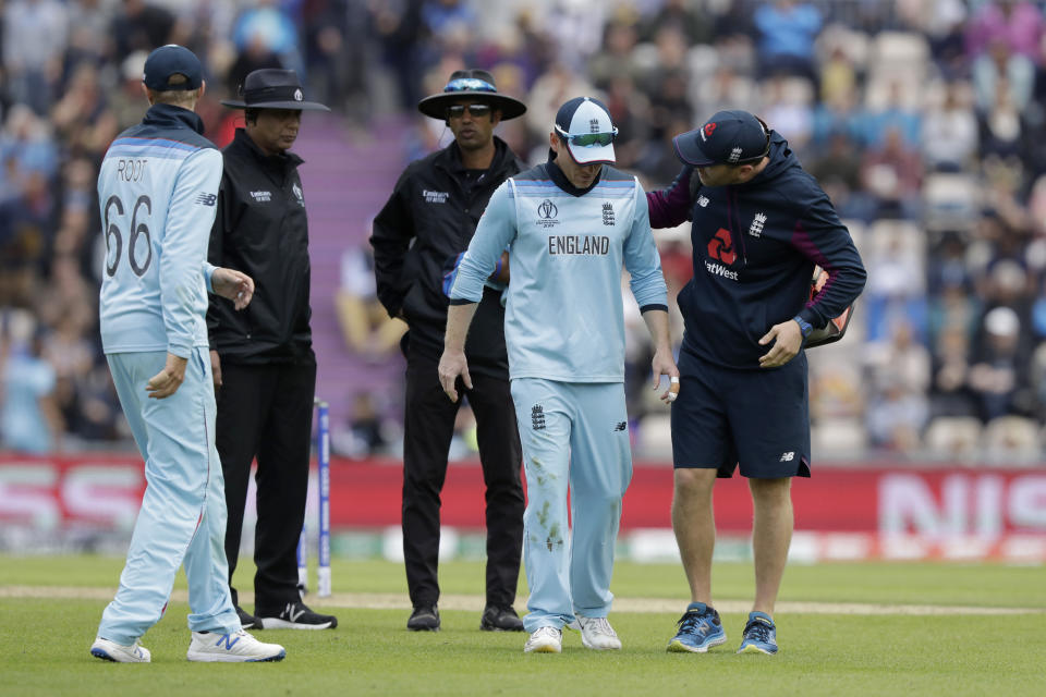 England's captain Eoin Morgan, second right, hobbles off the field of play with an injury, next to England's Joe Root, 66, during the Cricket World Cup match between England and West Indies at the Hampshire Bowl in Southampton, England, Friday, June 14, 2019. (AP Photo/Matt Dunham)