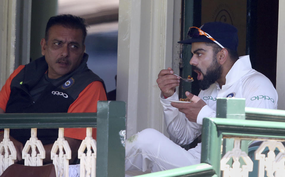 India's Virhat Kohli, right, eats while taking a break off the field during their tour cricket match against Cricket Australia XI in Sydney, Saturday, Dec. 1, 2018. (AP Photo/Rick Rycroft)