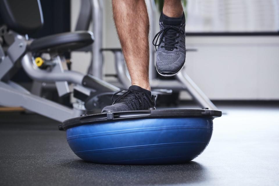 Ejercicios sobre un bosu, plataforma semiesférica con parte rígida que se utiliza para entrenar el equilibrio <a href="https://www.shutterstock.com/es/image-photo/dude-jogging-on-bosu-ball-gym-726681637" rel="nofollow noopener" target="_blank" data-ylk="slk:Shutterstock / the stock company;elm:context_link;itc:0;sec:content-canvas" class="link ">Shutterstock / the stock company</a>