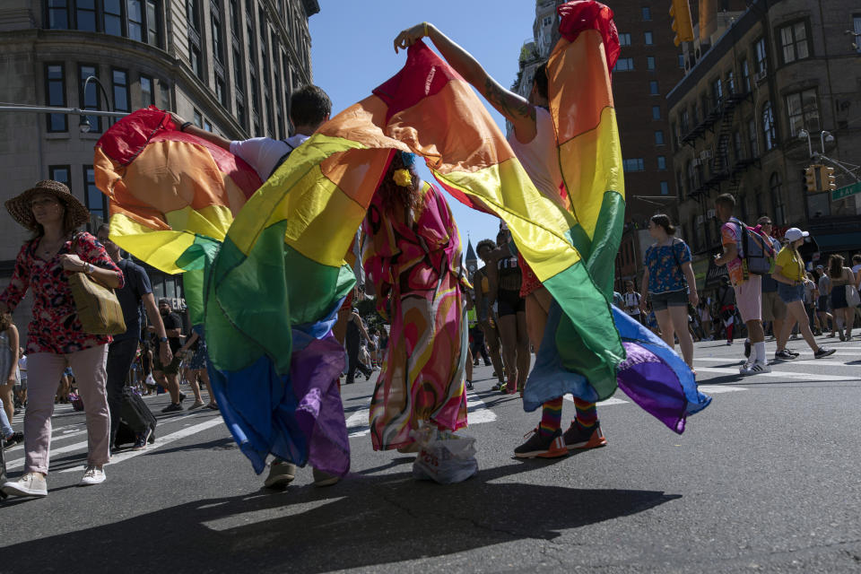 FILE - In this June 30, 2019, file photo, parade-goers pose for photographs with rainbow flags during the LBGTQ Pride march in New York. This year's Pride events were supposed to be a blowout as LGBTQ people the world over marked the 50th anniversary of the first parade to celebrate what were then the initial small steps in their ability to live openly, and to advocate for bigger victories. Now, Pride is largely taking a backseat, having been driven to the internet by the coronavirus pandemic and now by calls for racial equality that were renewed by the killing of George Floyd in Minneapolis at the hands of police. (AP Photo/Wong Maye-E, File)