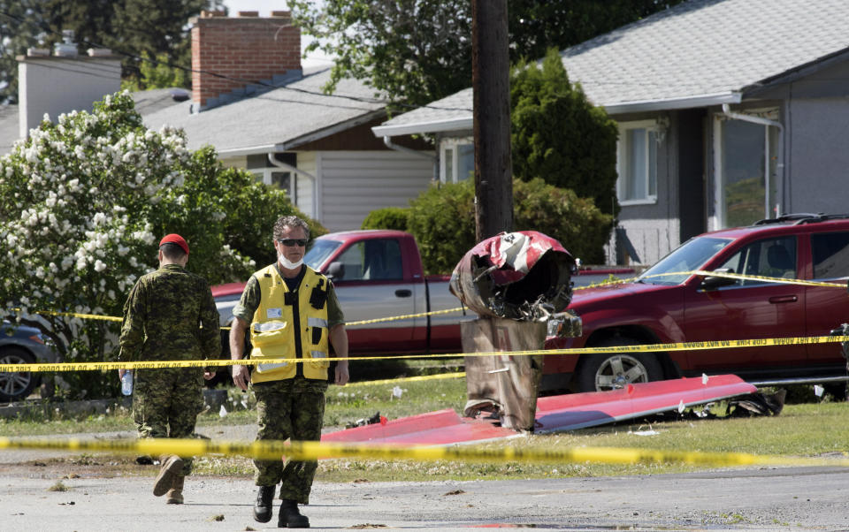 Members of the Canadian Forces walk past the tail section of a Snowbird jet in Kamloops, British Columbia, Monday, May 18, 2020. Capt. Jennifer Casey died Sunday after the Snowbirds jet she was in crashed shortly after takeoff. The pilot of the aircraft is in hospital with serious injuries. (Jonathan Hayward/The Canadian Press via AP)