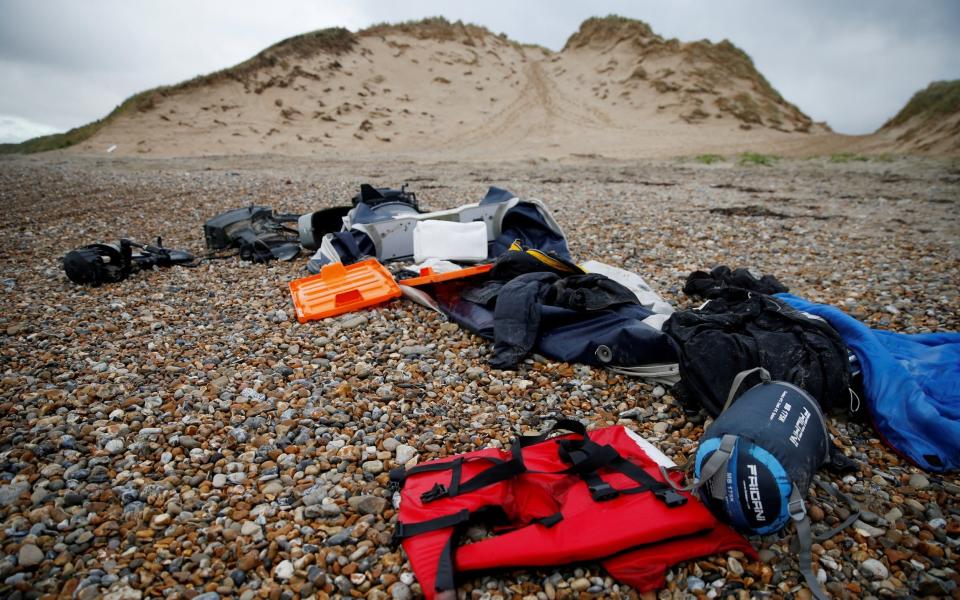 A damaged inflatable dinghy, outboard motors, life jackets and sleeping bags abandoned by migrants are seen on the beach near the Slack dunes, the day after 27 migrants died when their dinghy deflated as they attempted to cross the English Channel - Pascal Rossignol/REUTERS/ TPX IMAGES OF THE DAY