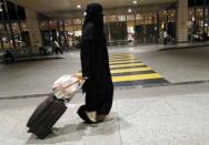 FILE PHOTO: A Saudi woman walks with her luggage as she arrives at King Fahd International Airport in Dammam
