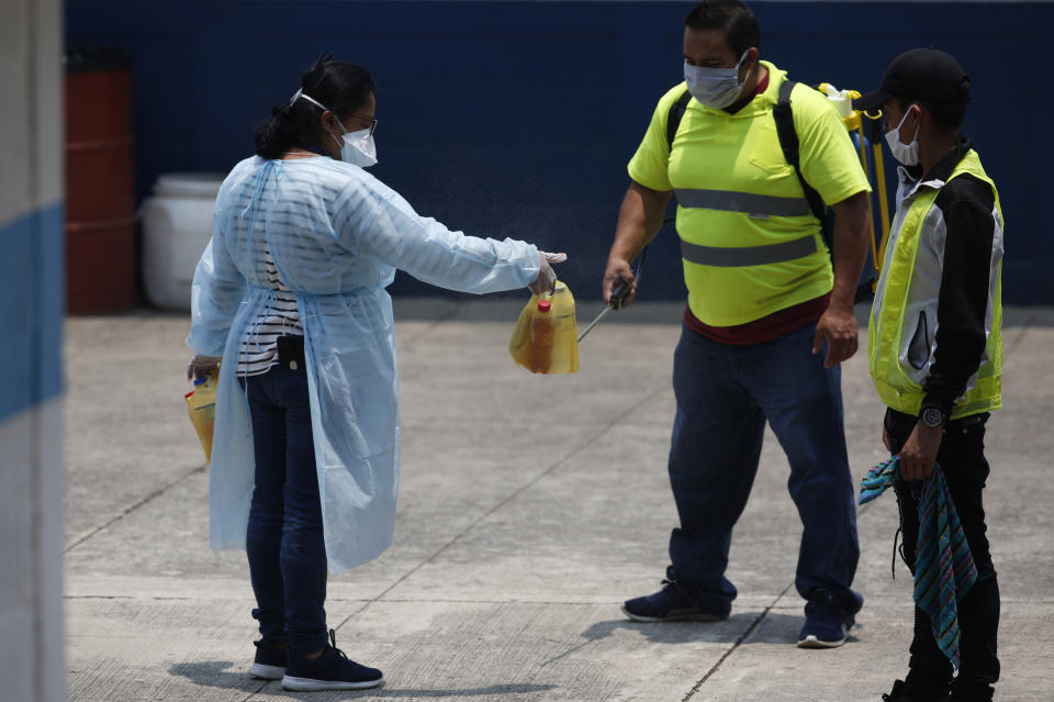 Workers disinfect bags of food brought by family members of deported Guatemalans being held at this site in Guatemala City, Friday, April 17, 2020. Recently deported Guatemalans were placed in a athletic dorm facility to wait for the results of their tests for the new coronavirus. (AP Photo/Moises Castillo)