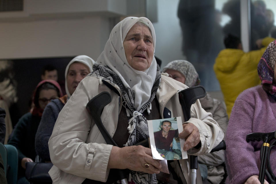 A woman holds a photo of her son, a victim of the Srebrenica genocide, as she awaits the decision of the UN appeals judges on former Bosnian Serb leader Radovan Karadzic in Potocari, Bosnia and Herzegovina, Wednesday, March 20, 2019. United Nations appeals judges on Wednesday upheld the convictions of Karadzic for genocide, war crimes and crimes against humanity, and increased his sentence from 40 years to life imprisonment. (AP Photo/Marko Drobnjakovic)