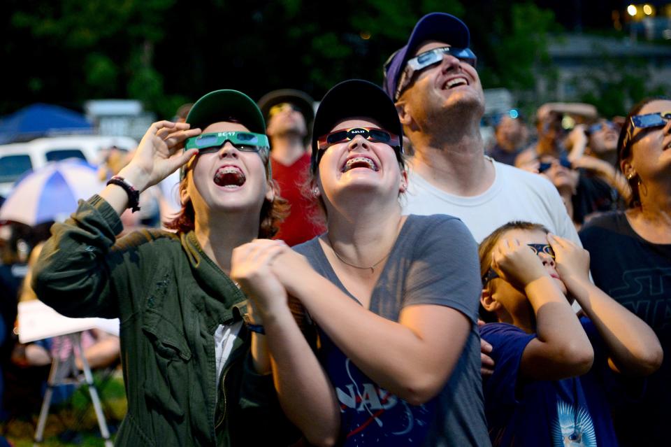 Ellie and Sydney Lang, 15 and 14 respectively, of Chapel Hill, react as the solar eclipse reaches totality at Bridge Park in Sylva, North Carolina on Monday, Aug. 21, 2017. 