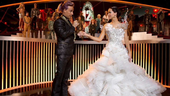 A man holds a woman's hand in The Hunger Games Catching Fire.