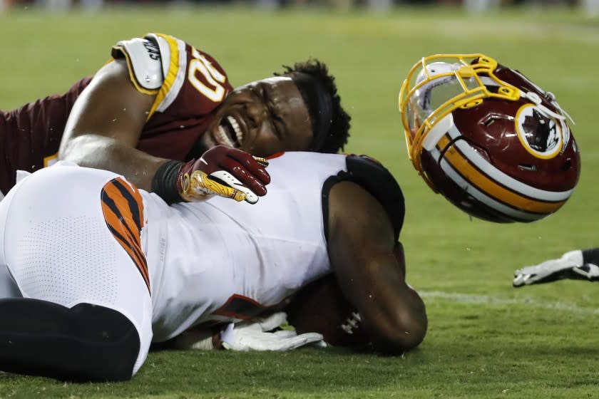 Washington Redskins linebacker Josh Harvey-Clemons (40) loses his helmet as he tackles Cincinnati Bengals wide receiver Auden Tate during the first half of an NFL preseason football game Thursday, Aug. 15, 2019, in Landover, Md. (AP Photo/Alex Brandon)