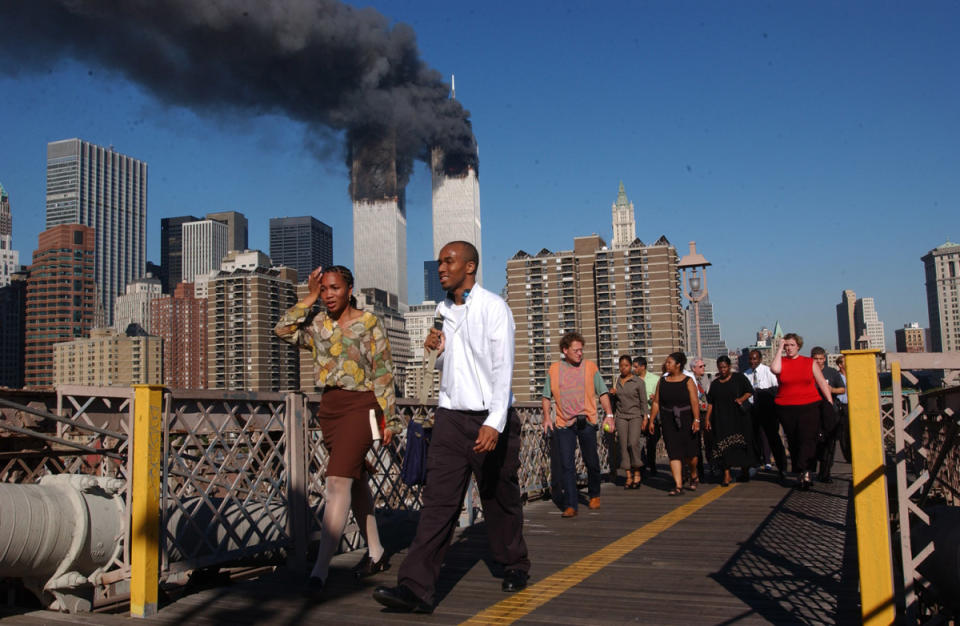 <p>Spencer Platt/Getty Images</p><p>People walk over the Brooklyn Bridge as the World Trade Center burns.</p>