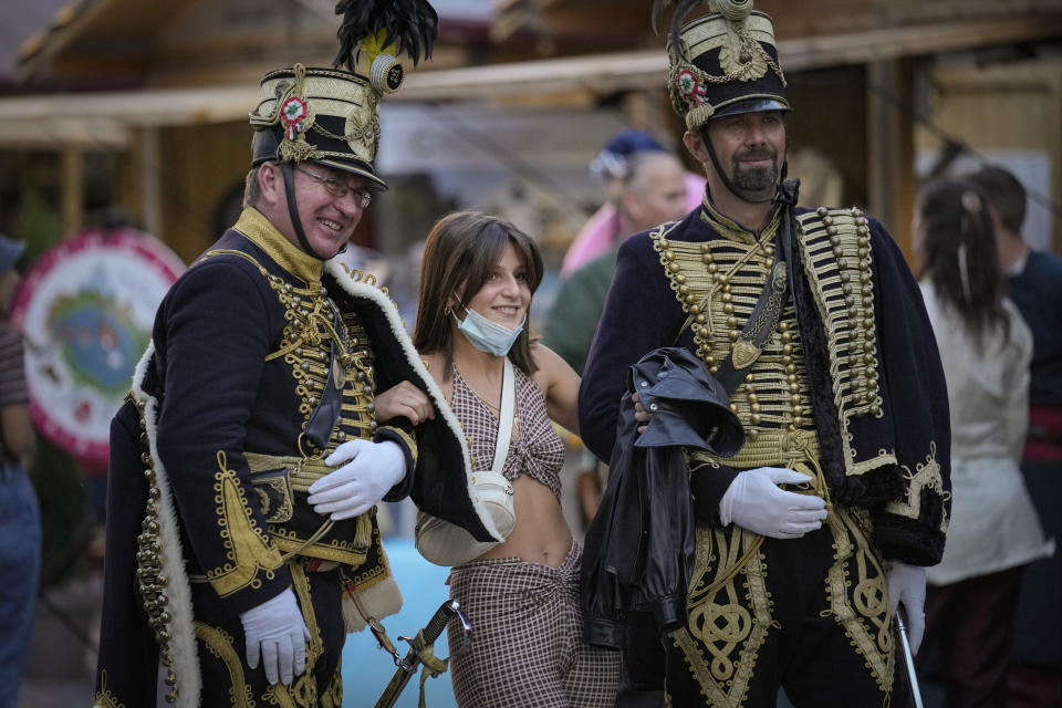 A young female poses with men wearing vintage Hungarian military uniforms at a fair outside the St. Stephen's Basilica in Budapest, Hungary, Friday, Sept. 10, 2021. Pope Francis is making his first foreign trip since undergoing intestinal surgery in July. His four-day visit to Hungary and Slovakia starting Sunday will not only test his health but also provide what may be one of the most awkward moments of his papacy — a meeting with Hungarian Prime Minister Viktor Orban, the sort of populist, right-wing leader Francis scorns. (AP Photo/Vadim Ghirda)