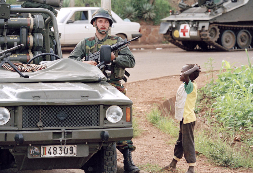 FILE - A young Rwanda boy looks at a Belgian soldier in defensive position during a halt of a UN convoy in Kigali, Rwanda, April 13, 1994. The soldiers' mission is to evacuate all foreign citizens from Rwanda to protect them from being massacred by the warring Hutu and Tutsi factions. (AP Photo/Jean-Marc Bouju, File)
