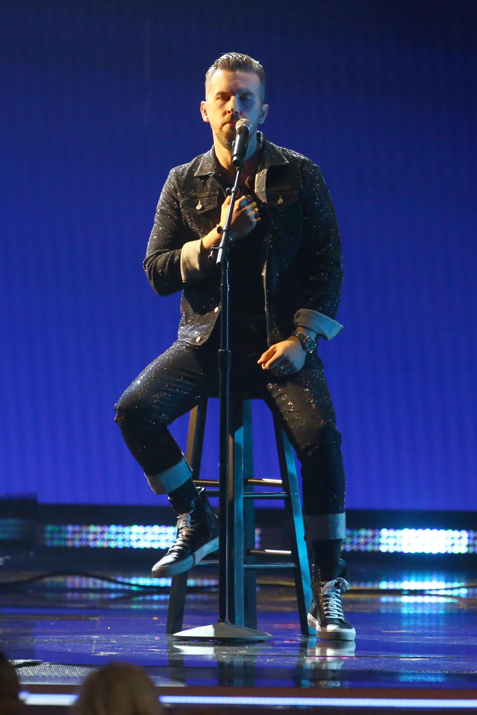 T.J. sits on a stool as he sings at the CMA awards