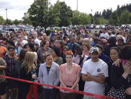 Parents wait behind police tape for students from Reynolds High School to arrive by bus in Troutdale, Oregon June 10, 2014. REUTERS/Steve Dipaola