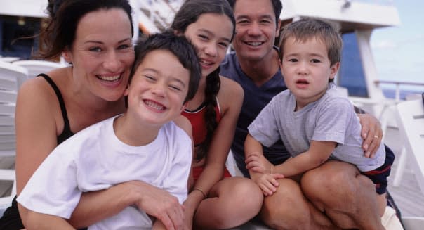 Parents with sons (4-5) (6-7) daughter (10-11) sitting on deckchair, portrait